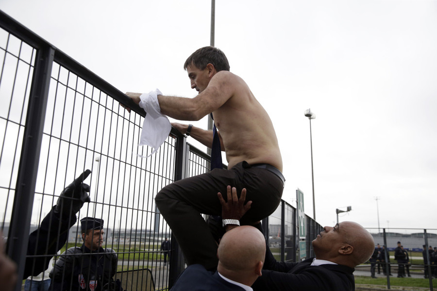 Air France Executive Vice President in charge of Human Resources and Labour Relations Xavier Broseta tries to cross a fence, helped by security and police officers, after several hundred employees stormed the offices of Air France on October 5, 2015. © Kenzo Tribouillard