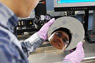 The face of an I.B.M. research scientist, Hongsik Park, is reflected in a wafer used to make microprocessors.