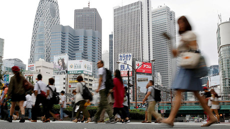 People cross a street in front of high-rise buildings in the Shinjuku district in Tokyo © Toru Hanai