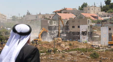 A Palestinian man watches Israeli heavy machinery as they demolish vacant apartment blocs by order of Israel's high court, in the West Bank Jewish settlement of Beit El near Ramallah July 29, 2015. © Mohamad Torokman
