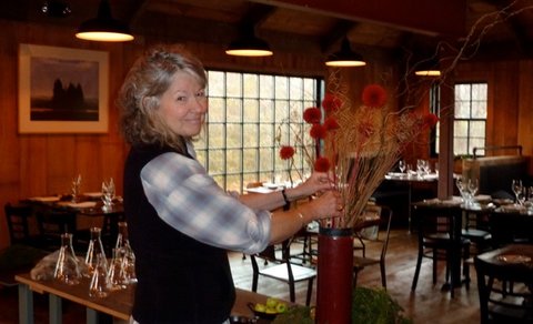 The owner's wife, adjusting a floral display, in the dining room.
