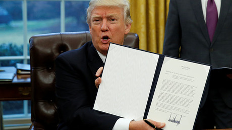 U.S. President Donald Trump holds up the executive order on withdrawal from the Trans Pacific Partnership after signing it in the Oval Office of the White House in Washington January 23, 2017. © Kevin Lamarque