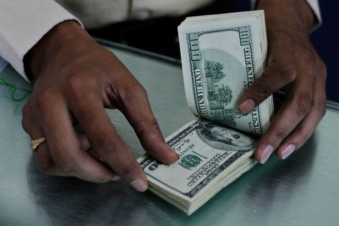 A man counting U.S. dollars at a Western Union money transfer outlet in Ahmedabad, Gujarat.