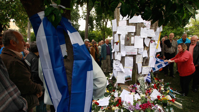 A mourner (R) places a Greek flag at the spot where a man committed suicide at central Syntagma square in Athens, April 5, 2012.(Reuters / John Kolesidis )