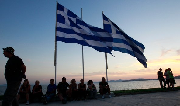 Supporters of the extreme right Golden Dawn party sit below Greek flags during an election campaign rally in Athens on Monday, June 11.