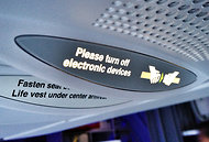 A sign on a Virgin America flight tells passengers to turn off electronic devices.