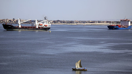 A fisherman travels on a boat front of container ships in the Suez canal near Ismailia port city, northeast of Cairo © Amr Abdallah Dalsh