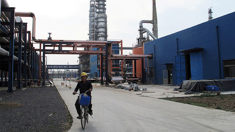 An employee rides a bike on a road near refinery plants of Chambroad Petrochemicals, in Boxing, Shandong Province, China. © Meng Meng