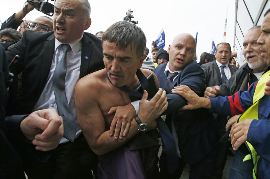 A shirtless Xavier Broseta, Executive Vice President for Human Resources and Labour Relations at Air France, is evacuated by security after employees interrupted a meeting with representatives staff at the Air France headquarters near Paris, France, October 5, 2015.© Jacky Naegelen