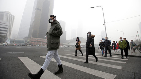 A man wearing a respiratory protection mask walks toward an office building during the smog after a red alert was issued for heavy air pollution in Beijing's central business district, China, December 21, 2016. © Jason Lee