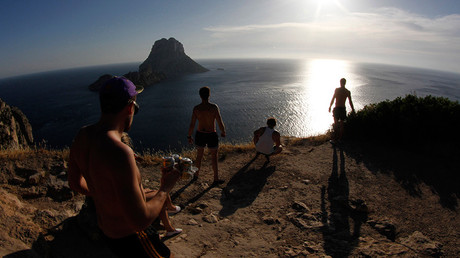 Tourists meet to watch the sunset at Es Vedra cliffs, on the Spanish Balearic island of Ibiza © Enrique Calvo
